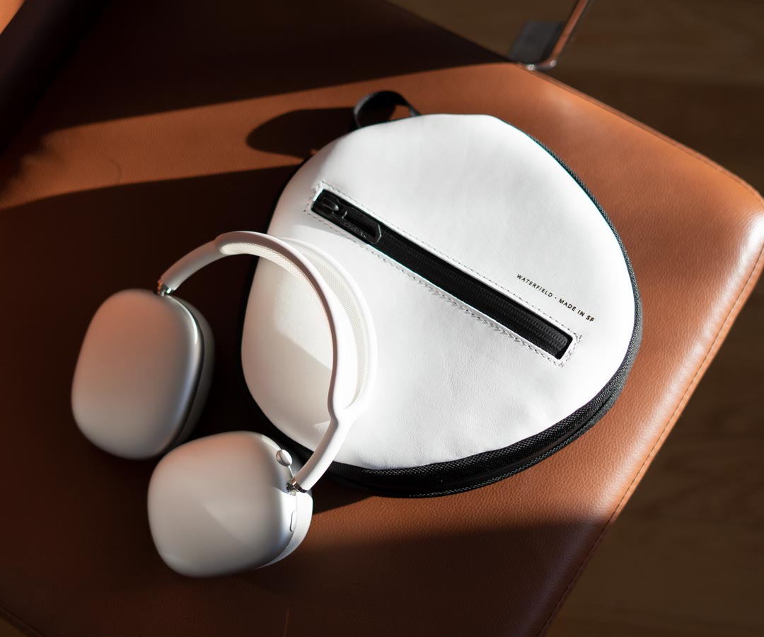 White AirPods Max headphones with round Vision Pro case on leather seat