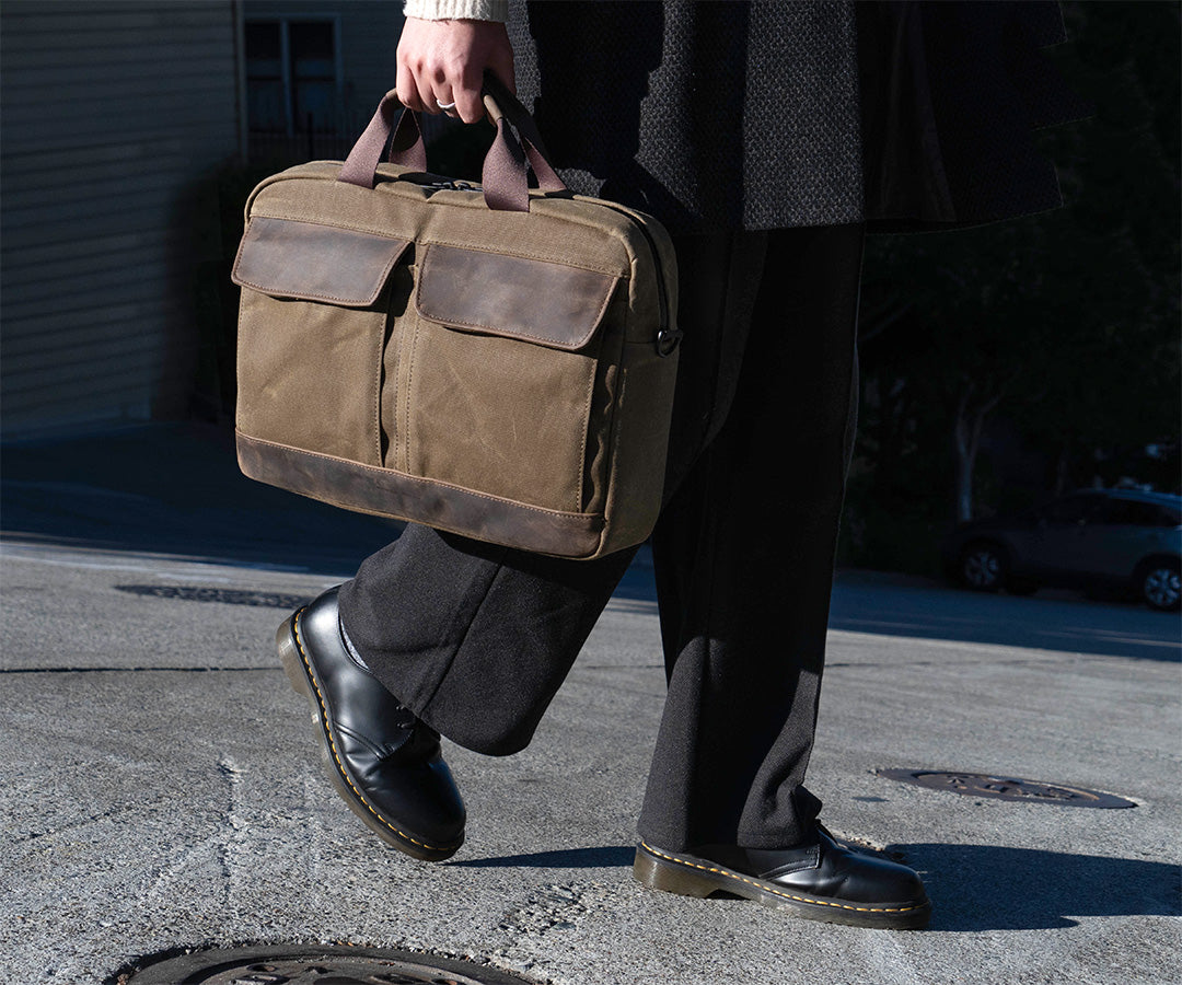 Person carrying structured brown leather briefcase while crossing street