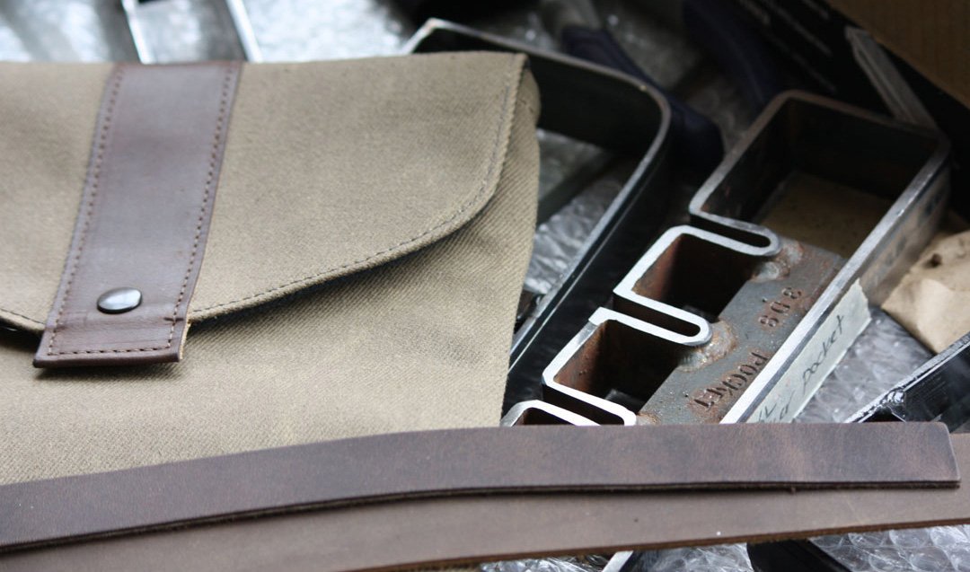 Handmade canvas and leather bag on a metal workbench in a San Francisco workshop